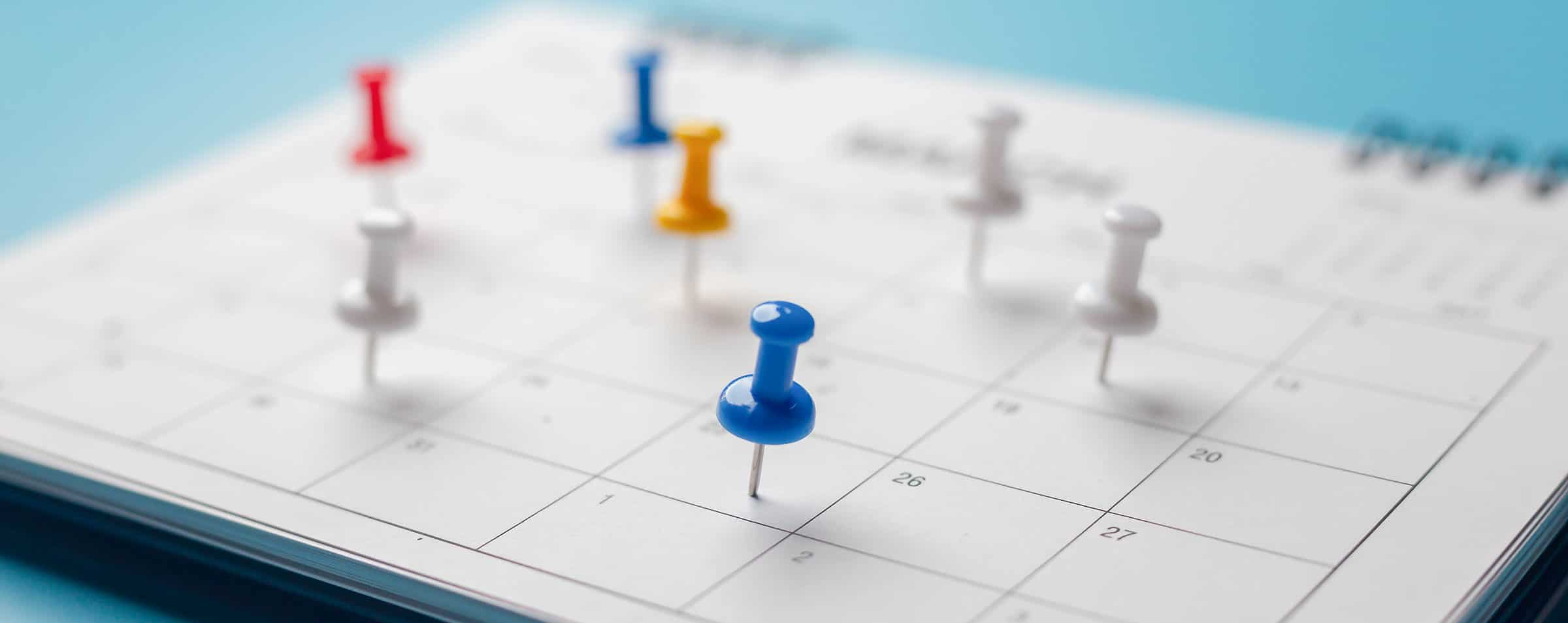 Decorative header photo of colored pushpins in a calendar marking important events or reminders